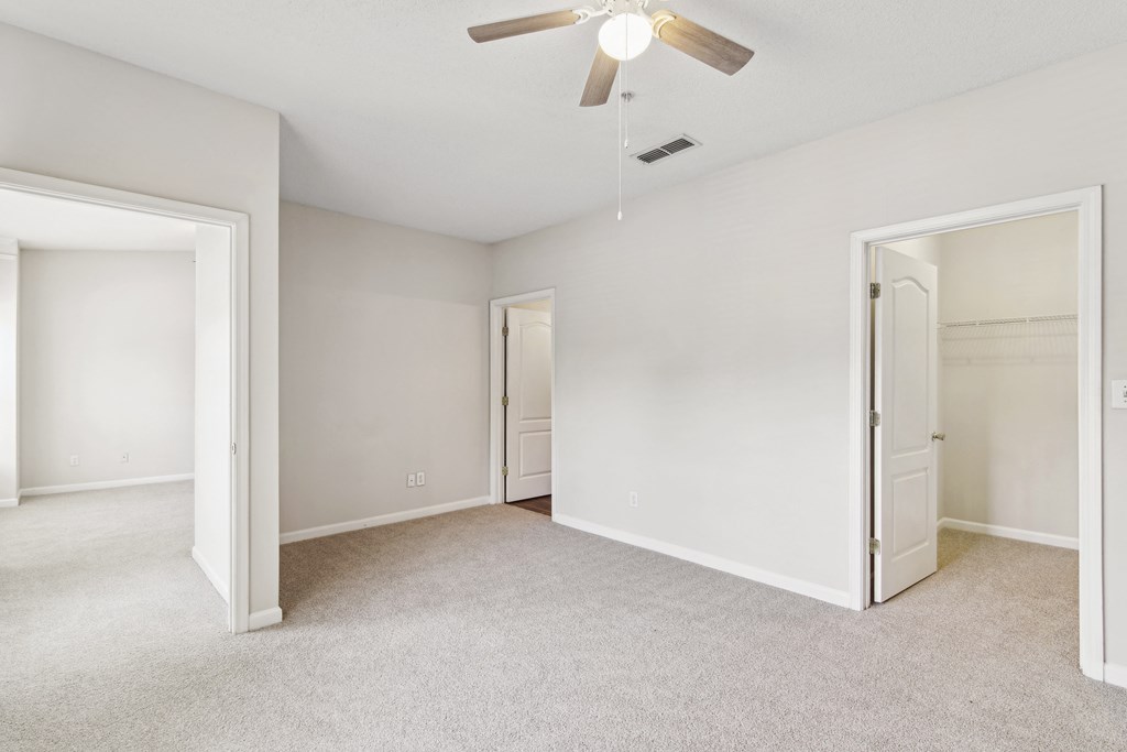 an empty bedroom with a ceiling fan and a closet