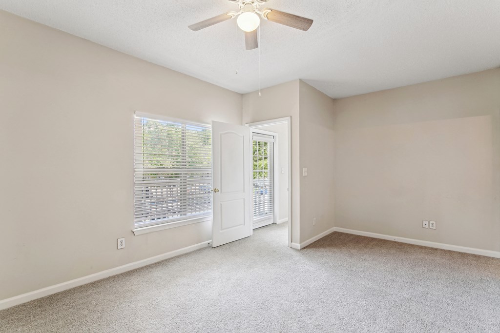 an empty living room with a ceiling fan and a window