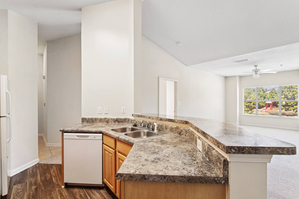 an empty kitchen with granite counter tops and a sink