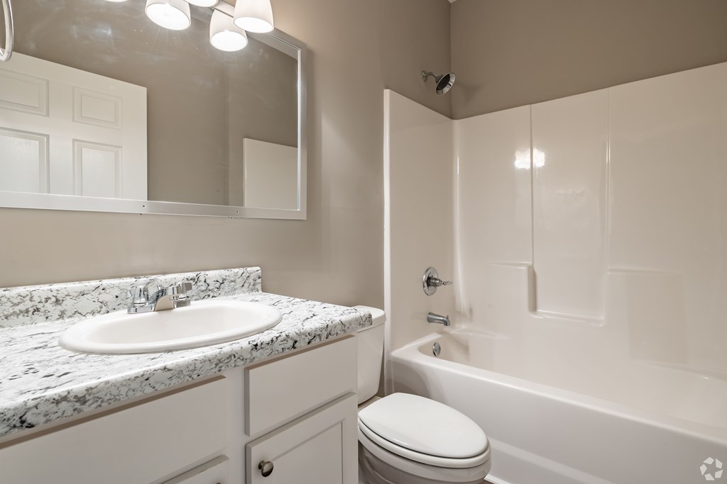 A white bathroom with a marble countertop and a white toilet at Club Villas Apartments, Kathleen, 31047