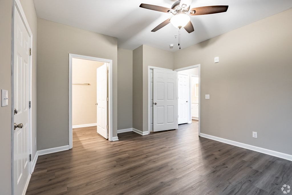 A room with a ceiling fan and wooden floors at Club Villas Apartments, Georgia