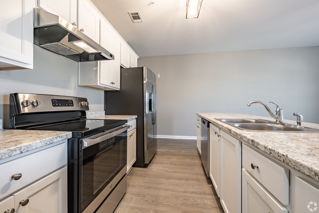 A kitchen with black and white appliances and cabinets at Club Villas Apartments, Kathleen, GA, 31047
