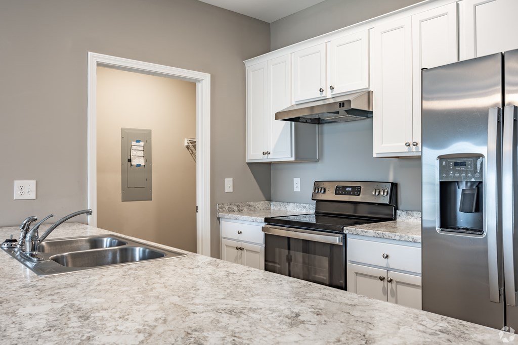 A kitchen with a granite countertop and stainless steel appliances at Club Villas Apartments, Kathleen, GA, 31047