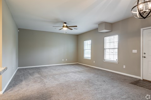 A spacious room with a ceiling fan and carpeted floor.