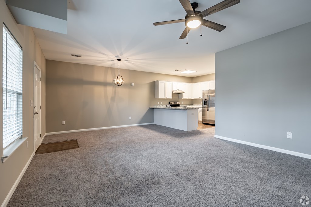 A spacious room with a ceiling fan and a kitchen area in the background at Club Villas Apartments, Kathleen