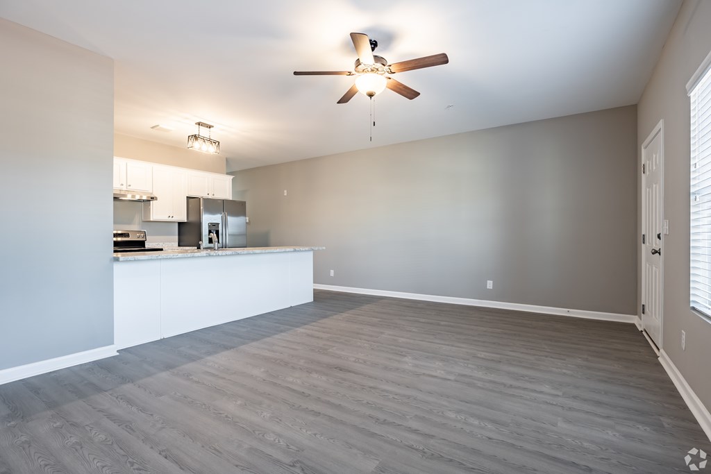 A spacious room with a ceiling fan and a kitchen area in the background at Club Villas Apartments, Georgia, 31047