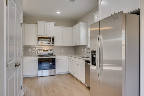 A modern kitchen with a stainless steel refrigerator and white cabinets.