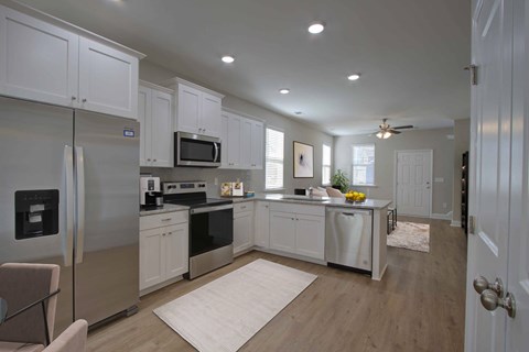 A kitchen with white cabinets and a refrigerator.