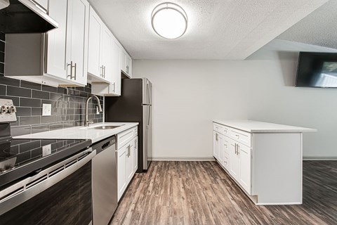 A kitchen with white cabinets and a black refrigerator.