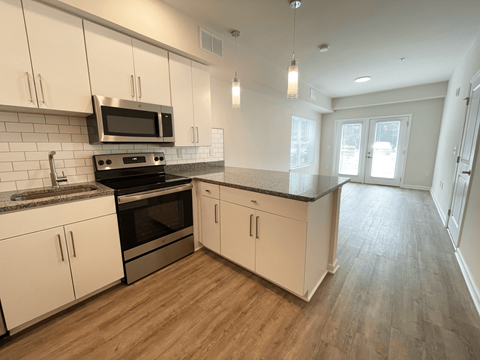 A kitchen with white cabinets and a black microwave at Emery Village, Concord, NC