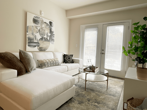 A living room with a white couch and a large abstract painting on the wall.