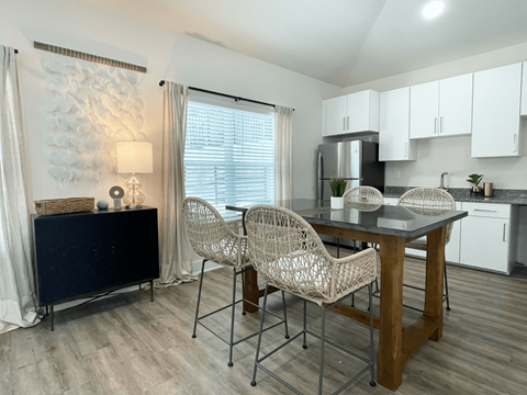 A kitchen with a table and chairs in the foreground and a refrigerator in the background.