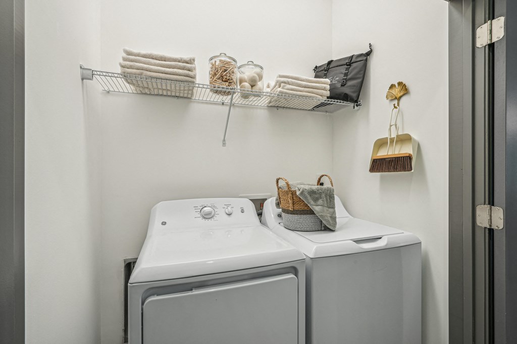 a washer and dryer in a white laundry room with a shelf above it at The Leo Myrtle Beach, South Carolina, 29579