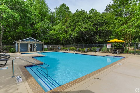 A pool surrounded by trees and a small building.