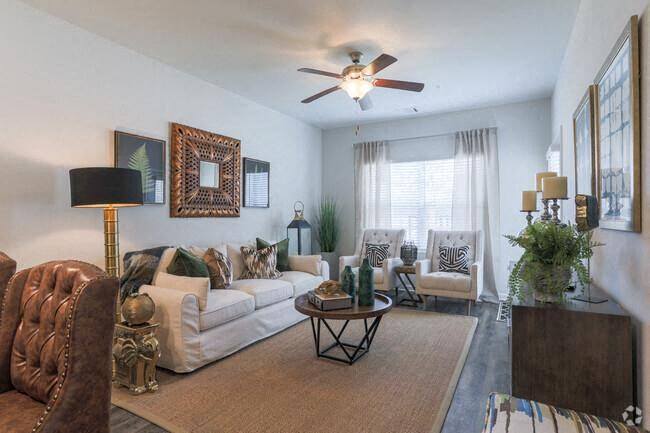 A living room with a white couch, a brown armchair, and a coffee table.