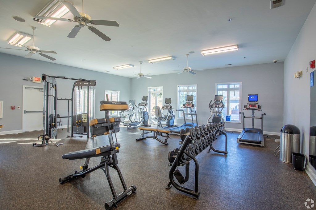 a fitness room with exercise equipment at the whispering winds apartments in pearland, tx