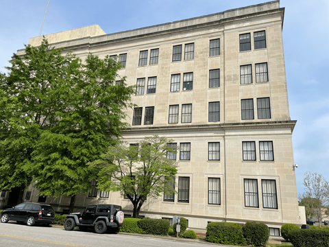 A large building with a lot of windows is in front of a tree.