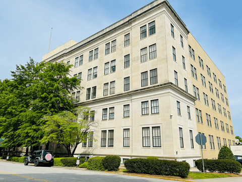 A large, two-story building with a flat roof and a mix of windows and shutters.