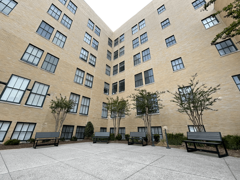 A courtyard with benches and trees surrounded by a brick building.