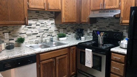 A kitchen with a black stove top oven and a black refrigerator.