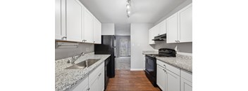 A kitchen with black appliances and white cabinets.
