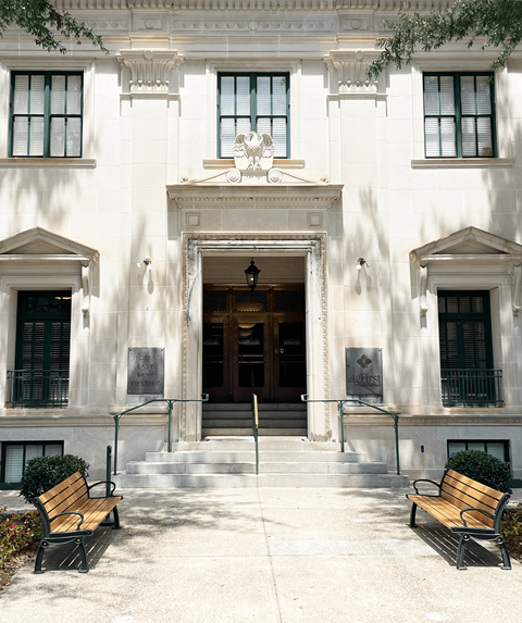 A white building with a black door and two windows on either side.