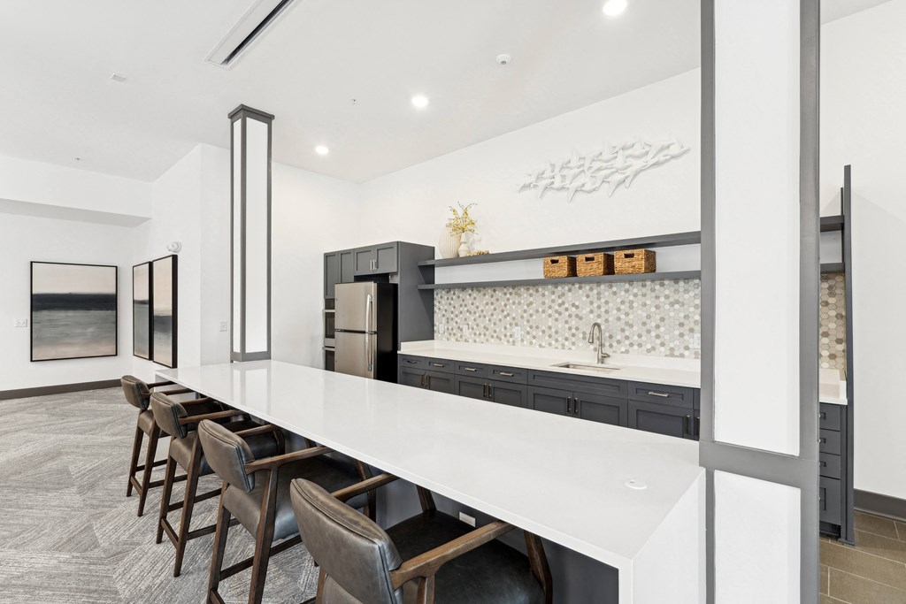 Kitchen with a long counter top and a long island with chairs at The Leo Myrtle Beach, Myrtle Beach, SC