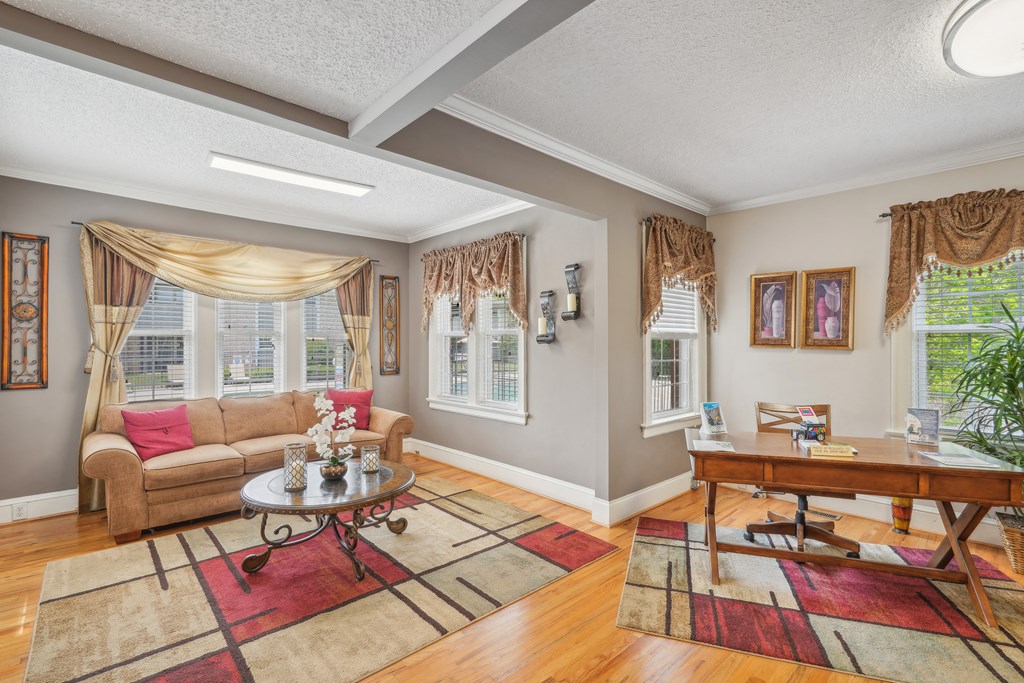 A living room with a couch, coffee table, and a window with curtains.