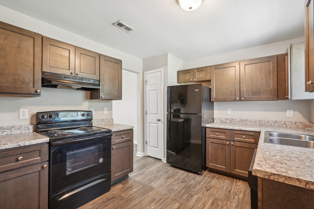 A kitchen with wooden cabinets and a black stove top oven at Lexington on the Green, North Carolina