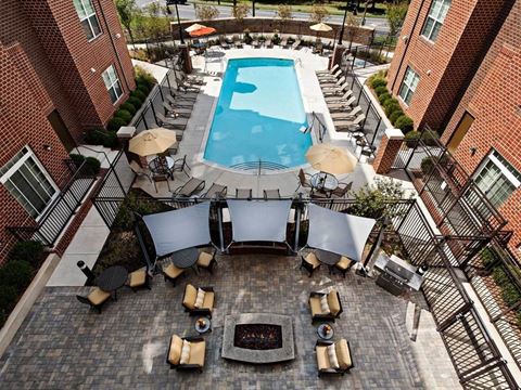 an aerial view of a pool and patio with chairs and umbrellas