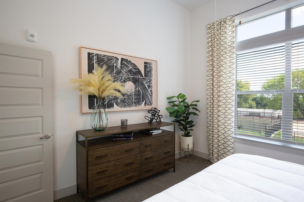 a bedroom with a bed and a dresser and a window at The Monroe Apartments, Austin, TX, 78741