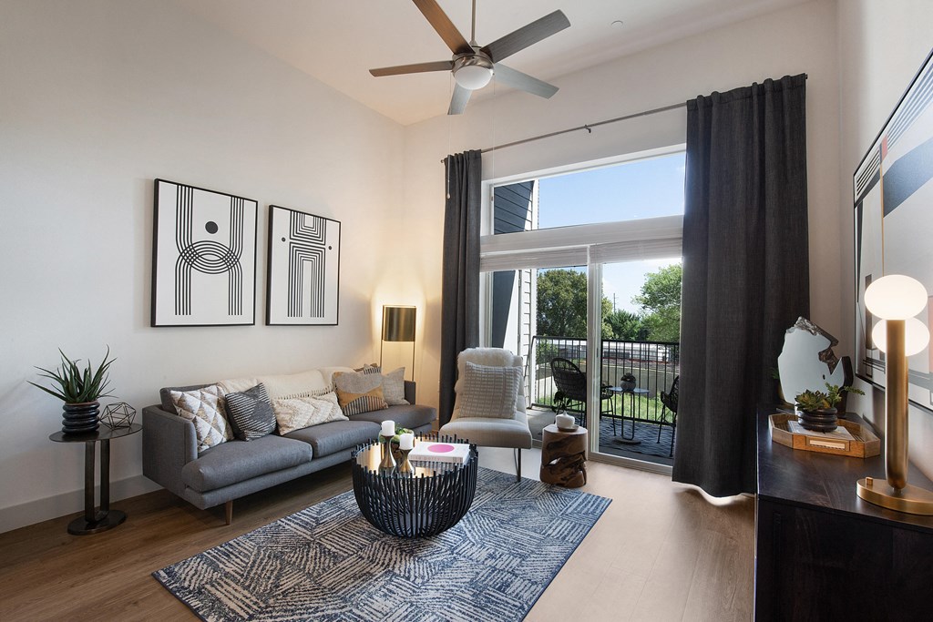 Open living room with a sliding glass door to a balcony at The Monroe Apartments, Austin, 78741