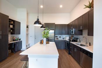 a large kitchen with a white island and dark cabinets at The Monroe Apartments, Austin, TX