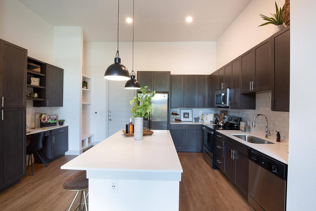 a large kitchen with a white island and dark cabinets at The Monroe Apartments, Austin, 78741
