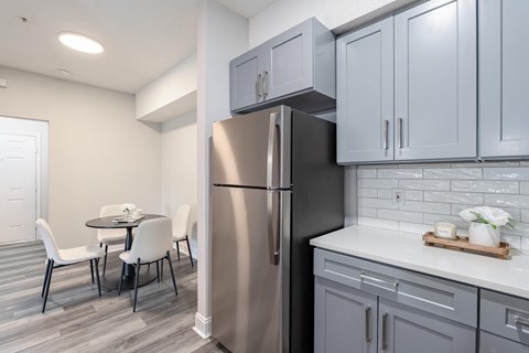 A kitchen with a refrigerator, table and chairs.