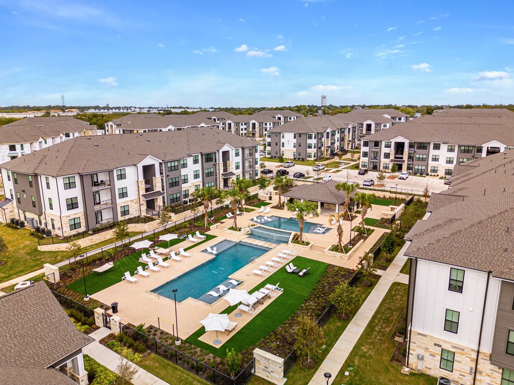 an aerial view of the resort style pool with lounge chairs and umbrellas at The Parker Austin, Pflugerville, Texas