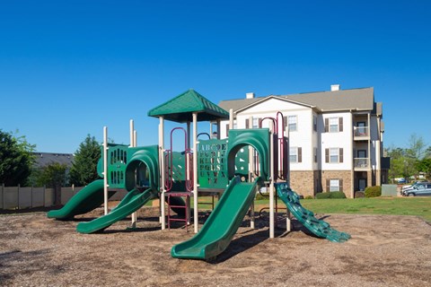 A playground with a green slide and a red and green play structure.