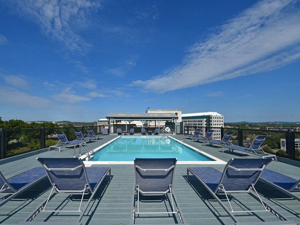 the pool on the roof of a hotel with blue chairs