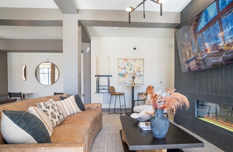 A living room with a brown couch and a large painting on the wall at The Delaney at East Park Apartments, Kennesaw, 30144