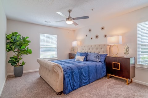 A bedroom with a blue bedspread and a white tufted headboard.