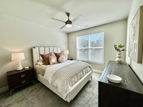 A bedroom with a large bed, a ceiling fan, and a nightstand with a lamp at The Collective Upper Westside Apartments, Atlanta, 30318