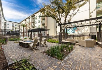 an outdoor patio with tables and chairs and a building in the background at The Monroe Apartments, Austin