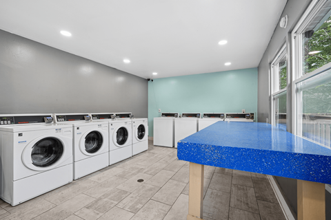 A laundry room with a blue counter and white washing machines.