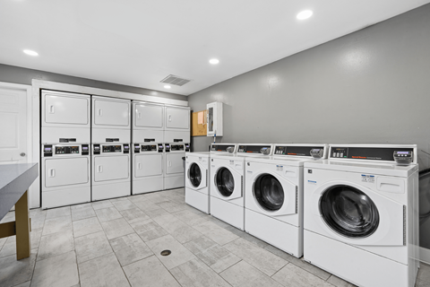 A row of white front load washing machines in a laundry room.