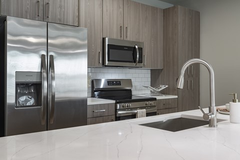 A modern kitchen with a stainless steel refrigerator, microwave, and oven at The Waverly at Winter Haven Apartments, Florida, 33884