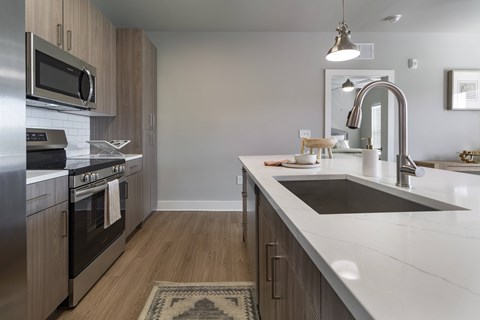 A modern kitchen with stainless steel appliances and wooden cabinets at The Waverly at Winter Haven Apartments, Florida, 33884