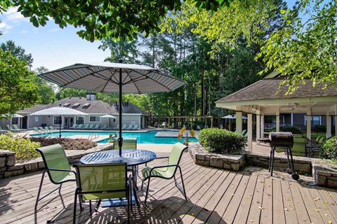 A pool area with a table and chairs and umbrellas.