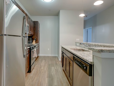 A kitchen with a refrigerator, oven, and sink.