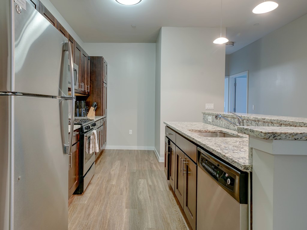 A kitchen with a refrigerator, oven, and sink.
