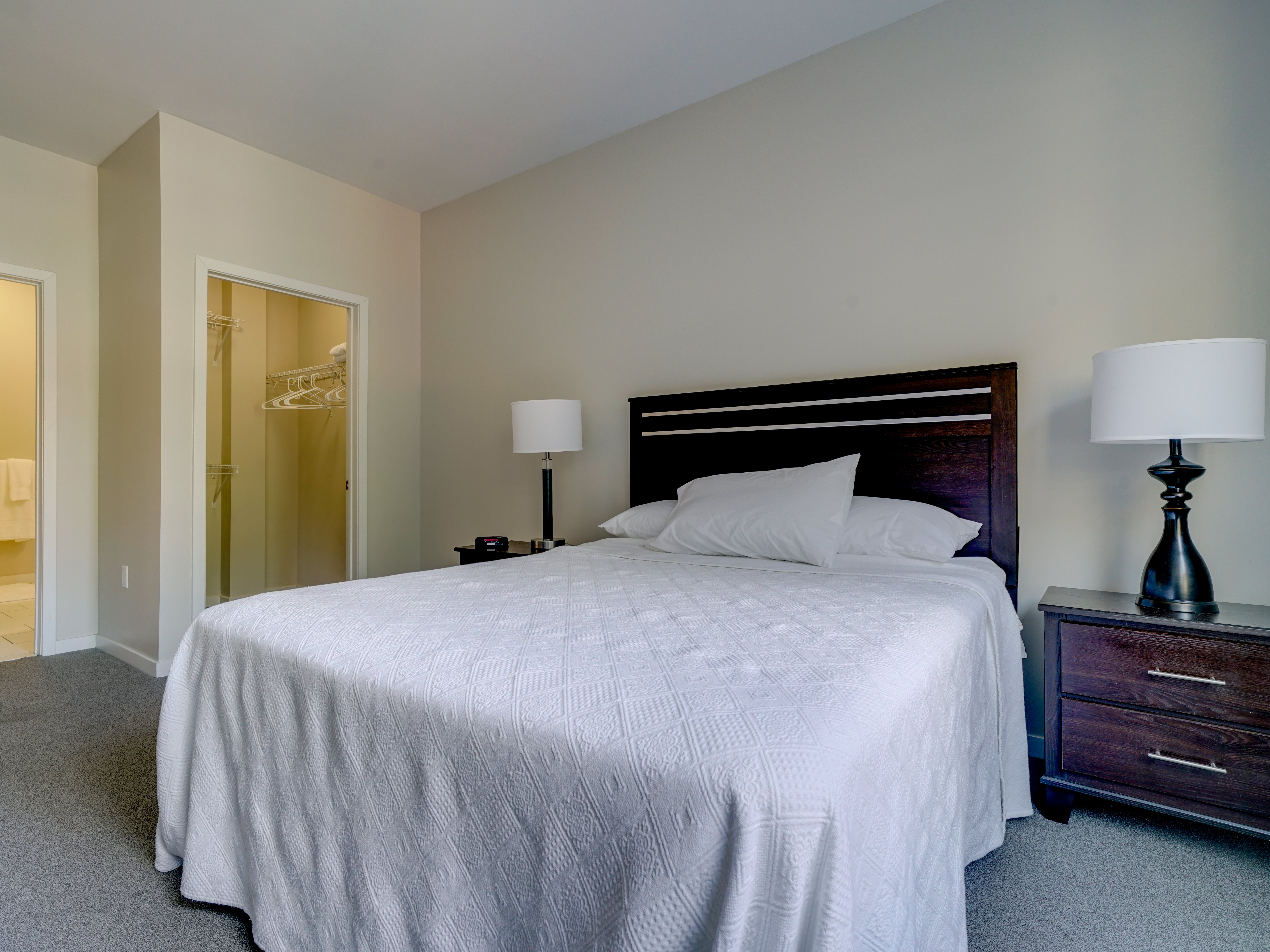 A bedroom with a large bed and two lamps.